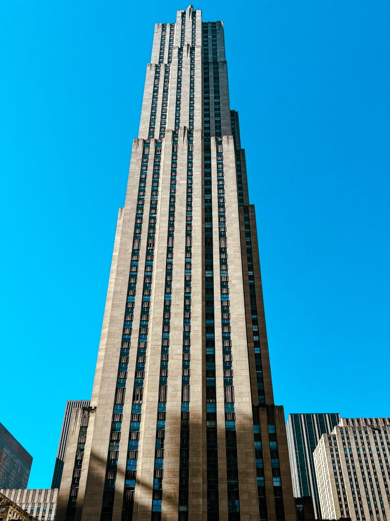 Manually straightened Photograph of the Rockefeller Center taken from the ground, looking up.